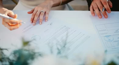 Imagem de um casal assinando documentos no casamento civil, em uma mesa simples, com caneta em mãos e clima formal.