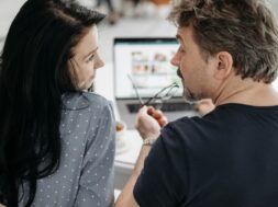 Casal juntos em mesa com notebook fazendo site de casamento.