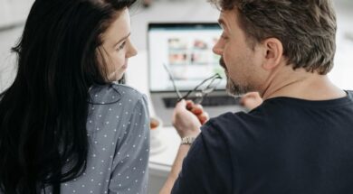 Casal juntos em mesa com notebook fazendo site de casamento.