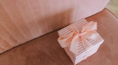 Caixa de presente decorada com laço rosa sobre um sofá, representando uma opção simples e elegante de presente de última hora de casamento.