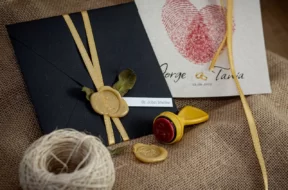 Convite de casamento com envelope preto, lacre de cera dourado e fita de cetim.