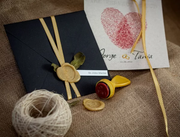 Convite de casamento com envelope preto, lacre de cera dourado e fita de cetim.