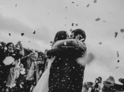 Casal de noivos se abraçando durante a cerimônia de casamento enquanto convidados celebram ao redor.
