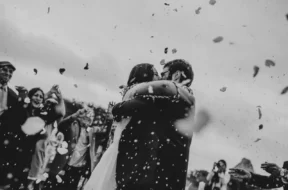 Casal de noivos se abraçando durante a cerimônia de casamento enquanto convidados celebram ao redor.