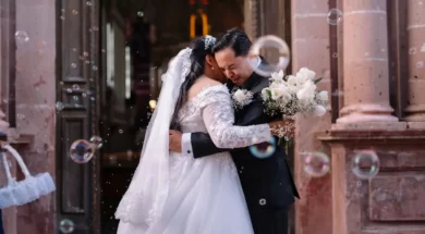 Noivos se abraçam na saída da cerimônia de casamento, cercados por bolhas de sabão.