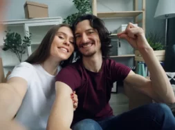 Casal sorrindo em casa enquanto segura as chaves do novo imóvel.