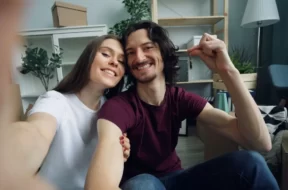 Casal sorrindo em casa enquanto segura as chaves do novo imóvel.