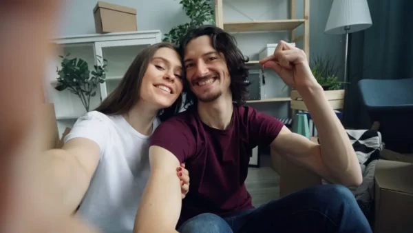 Casal sorrindo em casa enquanto segura as chaves do novo imóvel.